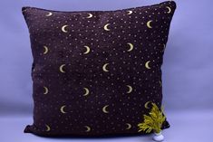 a decorative pillow with the moon and stars on it, sitting against a purple background