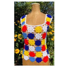 a crocheted top on a mannequin with yellow flowers in the background