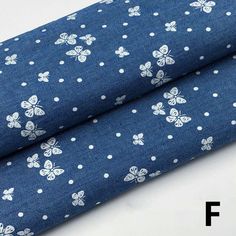 the fabric is blue with white flowers and dots on it, as well as an image of