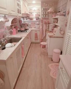 a kitchen with white cabinets and pink accessories