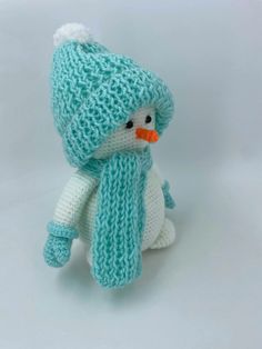 a small knitted snowman sitting on top of a white table