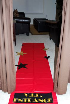 a red carpet with black stars on it in front of curtains and a door that leads to a living room