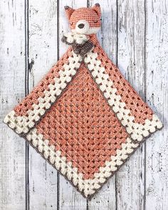 an orange and white crocheted blanket with a fox on it's back