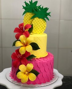 a three tiered cake decorated with pineapples and flowers