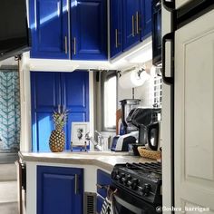 a blue and white kitchen with pineapple on the stove top in front of it