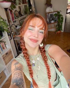 a woman with red hair and braids taking a selfie in her living room