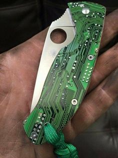 a person holding a green and white electronic device in their hand with it's blade sticking out