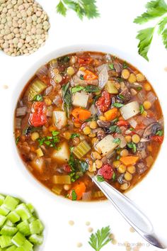 a white bowl filled with vegetable soup next to other vegetables