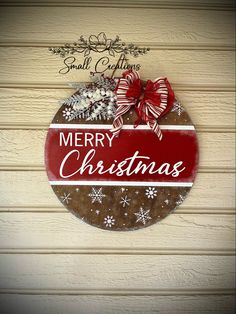 a merry christmas sign hanging on the side of a wooden wall with snowflakes