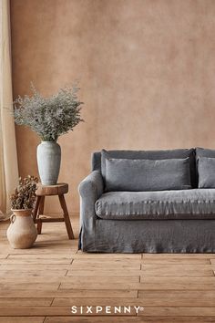 a living room with a couch, table and potted plant on the floor next to it