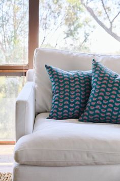 a white couch with two blue pillows on it