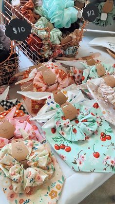 several different types of cloths are on display at a market table with baskets full of fabric