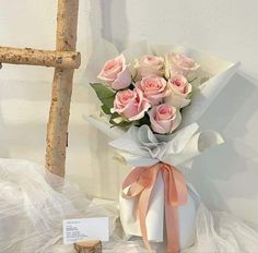 a bouquet of pink roses sitting on top of a table next to a wooden cross