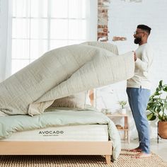 a man standing next to a bed with an overstuffed mattress