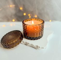 a lit candle sitting on top of a white table