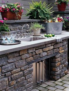 an outdoor kitchen with sink and potted plants on the outside wall next to it