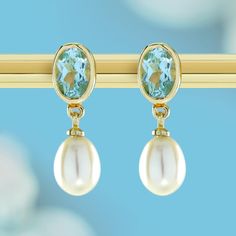 Step into timeless elegance with these vintage-inspired earrings, a captivating blend of classic elements and natural motifs. At the heart of each earring lies an oval-shaped blue topaz, nestled within a gold frame, radiating luxury and refinement. Connected by a small gold link, drop-shaped white pearls delicately dangle, infusing the design with a touch of sophistication and grace. These earrings would be a perfect accessory for formal events or as a statement piece for special occasions.  CHA Luxury Blue Pearl Earrings For Anniversary, Luxury Blue Gemstone Pearl Earrings, Blue Gemstone Luxury Pearl Earrings, Blue Luxury Pearl Earrings With Gemstone, Luxury Blue Pearl Drop Earrings, Luxury Formal Earrings With Birthstone, Luxury Birthstone Earrings For Formal Occasions, Luxury Formal Birthstone Earrings, Classic Blue Topaz Earrings For Wedding