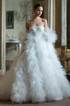 a woman in a white wedding dress with feathers on it