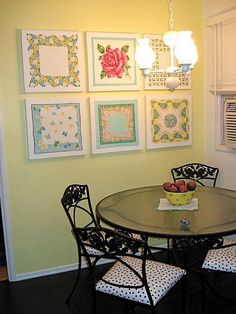 a dining room table with four chairs and pictures on the wall