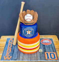 a cake with a baseball bat and glove on top, sitting on a wooden table