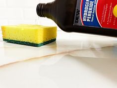 a yellow sponge sitting on top of a white counter next to a bottle of cleaner