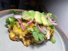 a taco salad on a plate with lettuce, onions and avocado