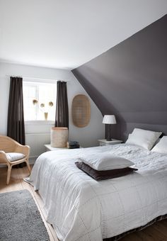 a bed room with a neatly made bed next to a chair and window in it