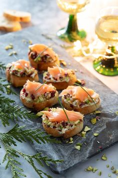 small appetizers with smoked salmon and herbs on a slate platter next to wine glasses