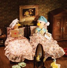 two stuffed ducks sitting on top of a wooden floor next to a dresser and mirror