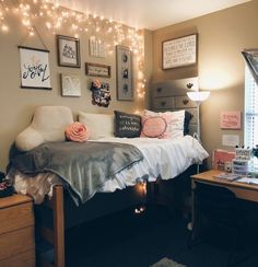 a bedroom with string lights strung above the bed and on the wall, there is a small desk in front of the bed