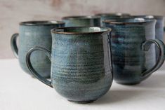 four coffee mugs sitting on top of a white table next to eachother