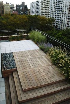 an outdoor deck with wooden steps and plants in the foreground, surrounded by high rise buildings