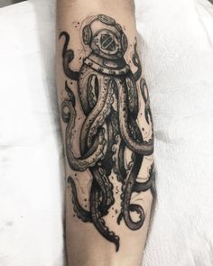 an octopus tattoo on the arm with a diver's helmet and tentacles around it