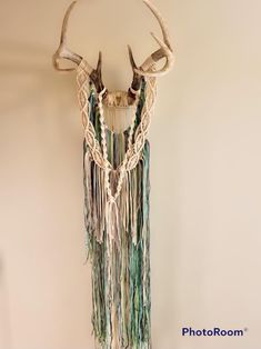 a deer's head hanging on the wall with some beads and other things attached to it