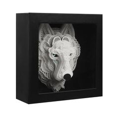 an intricately carved white wolf head in a black shadow box on a white background