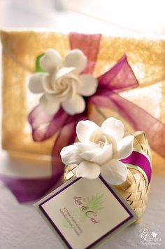 a white flower sitting on top of a table next to a gift box with a tag