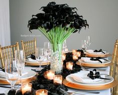 a table set with black flowers and candles