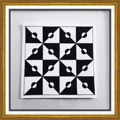 a black and white pattern is hanging in a gold framed art piece on the wall