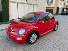 a red car parked in front of a building on a brick road next to a parking meter