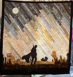 a person holding up a quilt that is made to look like a scene from star wars