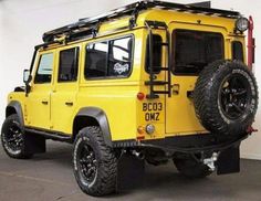 a yellow jeep parked in a garage next to a white wall with black lettering on it