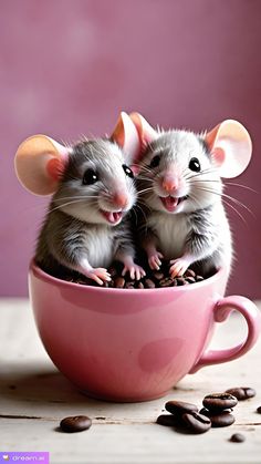 two little mice sitting in a pink cup with coffee beans on the table next to them