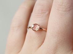 a woman's hand with a pink diamond ring on top of her left hand