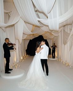 a bride and groom kissing in front of white draping at their wedding reception