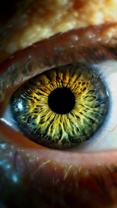 an extreme close up shot of the iris of a person's eye, with yellow and green colors