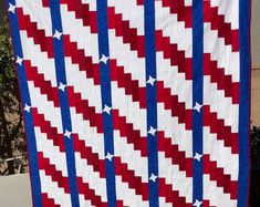 a red, white and blue quilt hanging from a pole