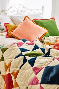 a bed with colorful quilts and pillows on it