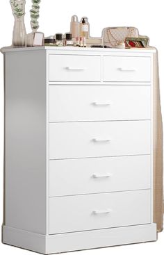 a white dresser with lots of items on it's top shelf and bottom drawer