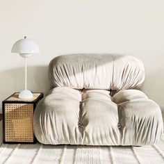 a white couch sitting on top of a wooden floor next to a lamp and table