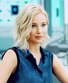 a woman with blonde hair and blue eyes is posing for a photo in an office